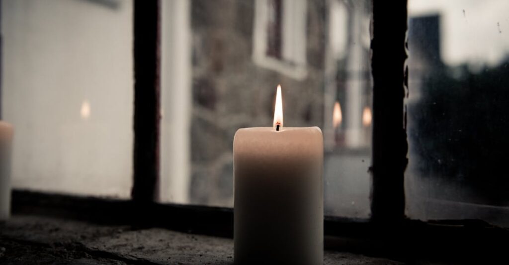 A lit candle by a window, offering a warm and cozy ambiance.