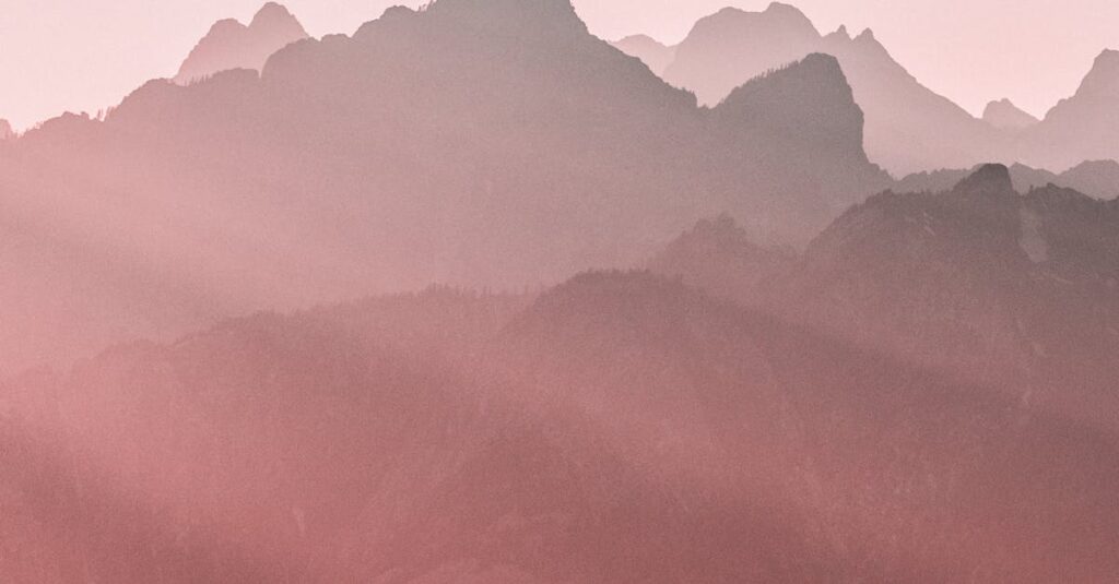 Peaceful pastel mountain landscape with soft light at sunrise, evoking tranquility.