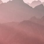 Peaceful pastel mountain landscape with soft light at sunrise, evoking tranquility.